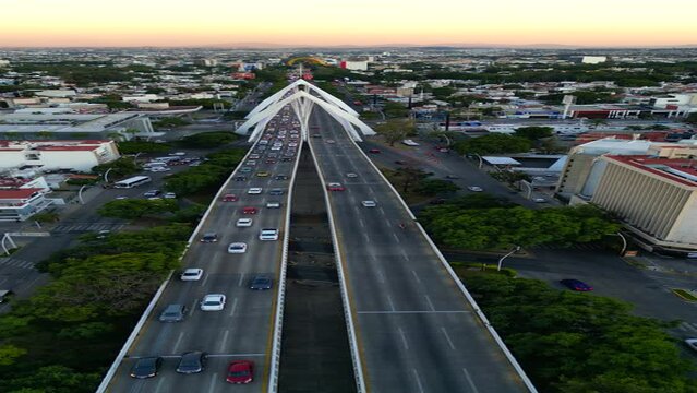 A sweeping vertical panoramic drone view capturing the steady flow of traffic on Guadalajara's Matute Remus Bridge