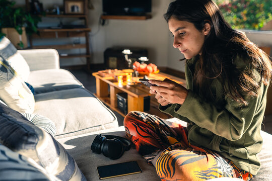young woman with her phone on her living room