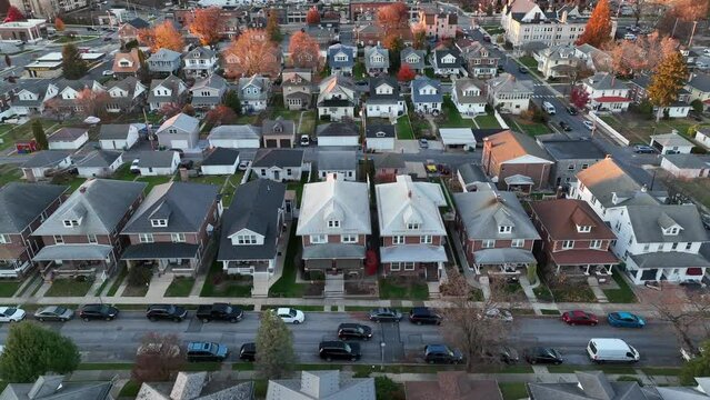Aerial view of a residential street with rows of gabled houses during autumn. Aerial truck shot.