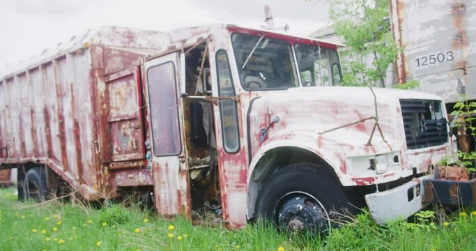 An old Garbage truck left to the elements in an open field.