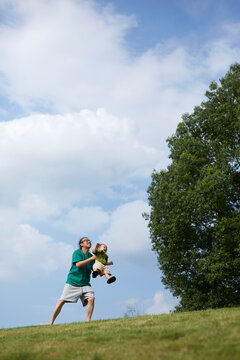 Asian father and son, having fun on the grass slope