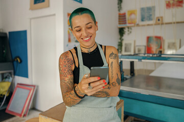 Smiling female worker use mobile phone during working day in design studio
