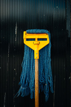 Cleaning mop with blue threads placed on black surface
