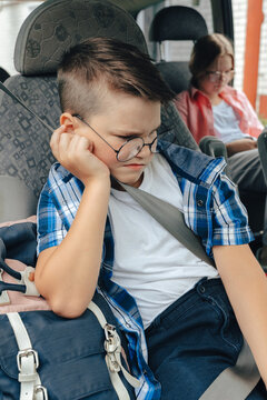 Unhappy sad upset school boy with backpack in car going back to school