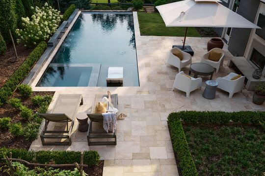 Top down view of a woman relaxing poolside with a book 