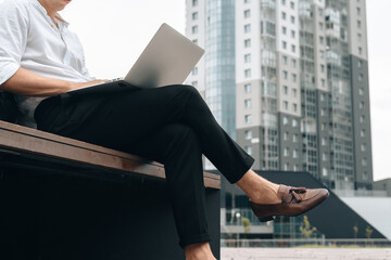Unrecognizable man working online on laptop outdoor