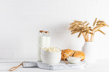 Fresh dairy products on a white wooden board and a vase with ears of corn on a wooden table....