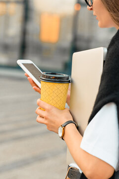 Young businesswoman with coffee, using phone checking calendar