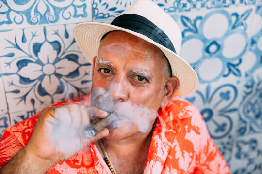 Senior cuban man in tropical outfit smoking a cigar