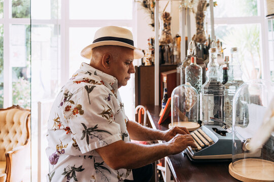 Old cuban man typing on vintage typewriter