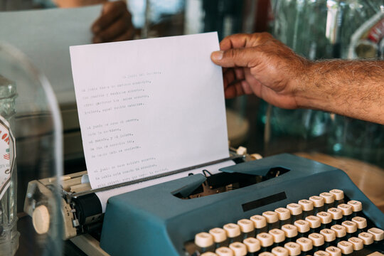 Crop man typing poem on vintage typewriter