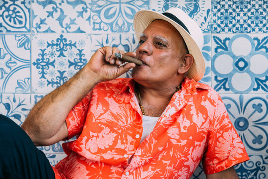Senior cuban man in tropical outfit smoking a cigar