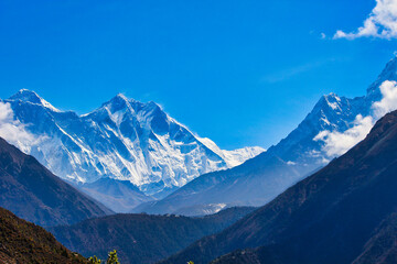 Beautiful image of the Everest Massif set against a blue sky behind deep valleys during the Everest Base camp trek near Namche Bazaar, Nepal - obrazy, fototapety, plakaty