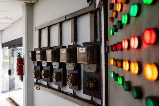 Old kWh meter circuit arrangement with old and rustic electrical control panel with red, green, and yellow lights inside a building