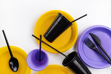  A set of disposable plastic tableware in lilac, yellow and black colors. Ecology and plastic waste recycling concept