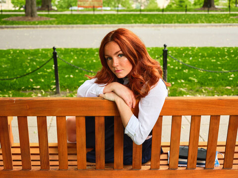 College redhead student girl sitting on the bench 