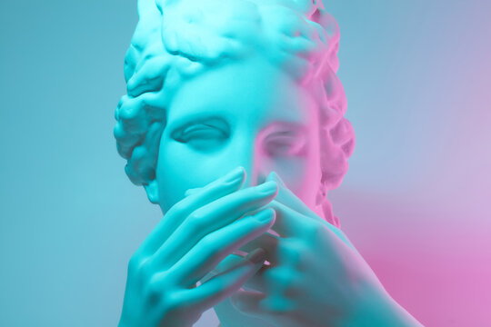 Gypsum statue covers mouth with both hands.