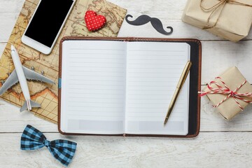 Fototapeta premium Top View Happy Father Day With Travel White Mobile Phone Notebook Rustic Wooden Background Accessories With Map Airplane Mustache Vintage Bow Tie Pen Present Red Heart