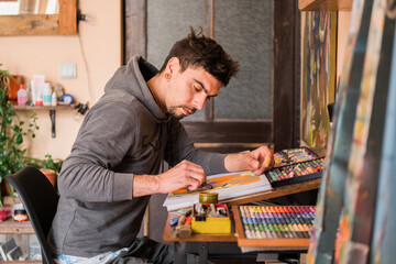 Male painter drawing abstract paintings using oil pastels