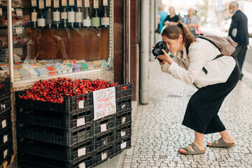 Woman taking photos of a box of cherries on the street