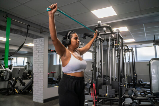 Plus Size Woman Exercise Using Resistance Band At Gym