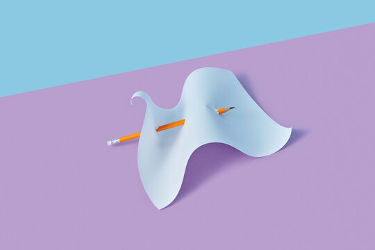 Pencil piercing through white paper sheet.