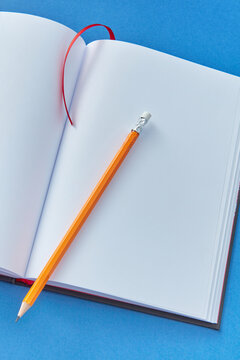 Close-up of open blank book with pencil.