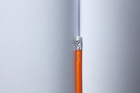 Close-up of pencil on pages of blank notebook.