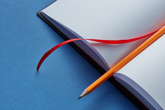 Blank book with pencil and red bookmark.
