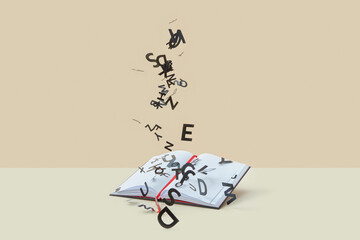 Black paper letters falling on blank notebook.