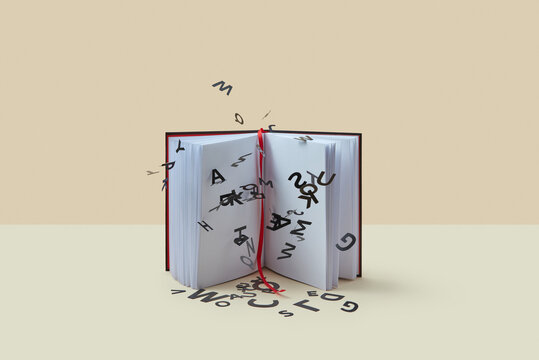 Open book with falling black paper letters.