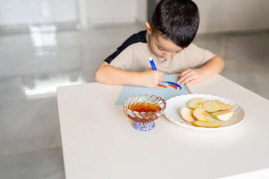 Rosh Hashanah Greetings. Boy Drawing Apple and Honey.