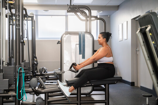 Plus Size Woman Working Out At Rowing Machine In The Gym