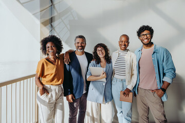 Diverse group of business professionals smiling and looking at camera in modern office