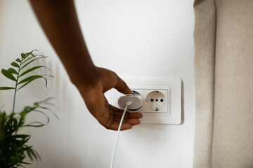 Woman Putting Plug Into Socket 