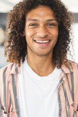 Young biracial man with curly brown hair smiles warmly