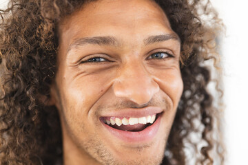 Young biracial man with curly hair smiles brightly