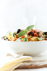 Pappardelle Pasta with cherry tomatoes, red onion and fresh basil on white wooden background.	
