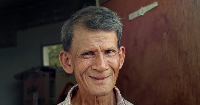 A smiling Asian man who is an elderly worker live in a poor house. Used in film concepts, humanity, documentaries and others.