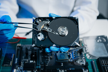 Obraz premium Hard disk drive on the technician's desk and a computer motherboard as a component. the concept of data, hardware, and information technology..