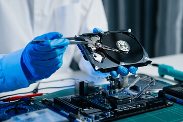  Hard disk drive on the technician's desk and a computer motherboard as a component. the concept of data, hardware, and information technology..