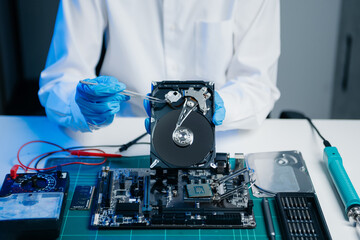  Hard disk drive on the technician's desk and a computer motherboard as a component. the concept of...