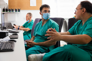 Doctors sitting and discussing at desk with gadgets