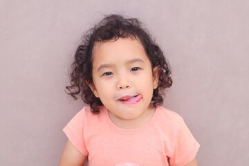 Fototapeta premium Expression of a toddler girl drinking milk in a glass.