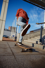 Hipster man riding skateboard on city street