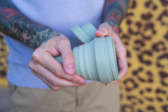Man with a tattoos open reusable cup for coffee