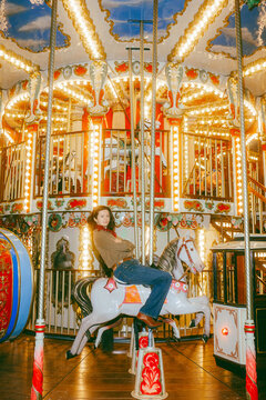An attractive girl on a bright children's carousel saddled a horse