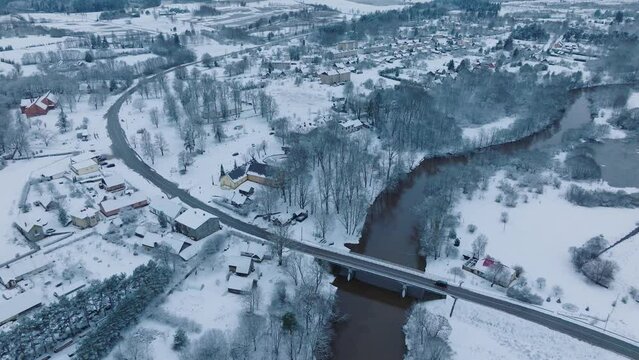 Abava river curving through snowy Renda village (Kuldiga parish, Latvia), winter scenery, aerial view