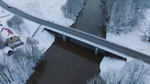 Abava river bridge near Renda village (Kuldiga parish, Latvia), snow-covered landscape, aerial view, birdseye orbit shot