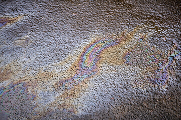 Oil stains from leaks in the car engine. Oil after rain makes spots with rainbow reflections...